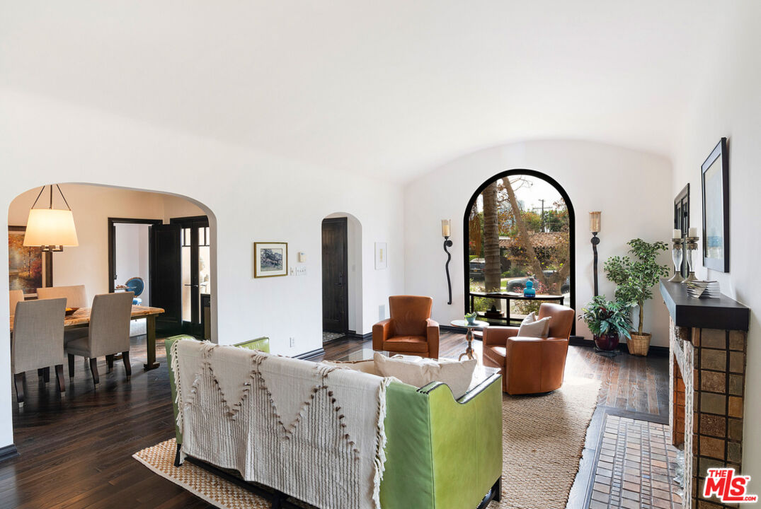 a living room with furniture a rug a fireplace and a potted plant