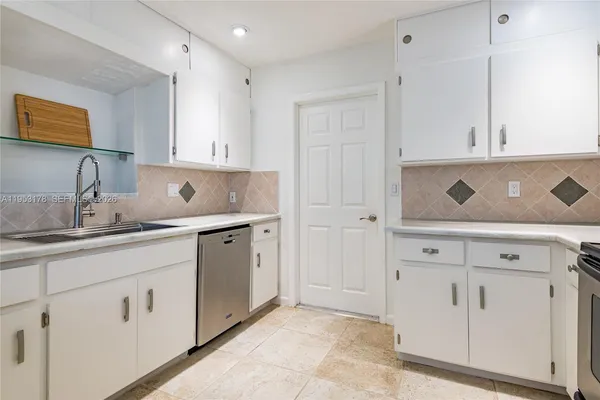 a kitchen with white cabinets and sink