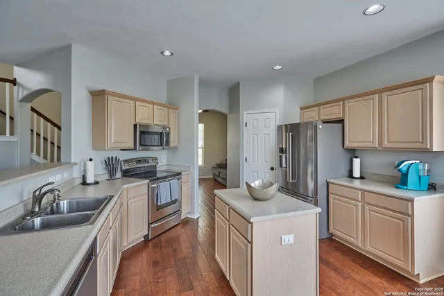 a kitchen with stainless steel appliances granite countertop a sink stove refrigerator and cabinets