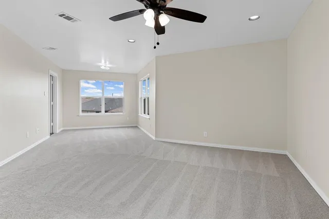 an empty room with chandelier fan and windows