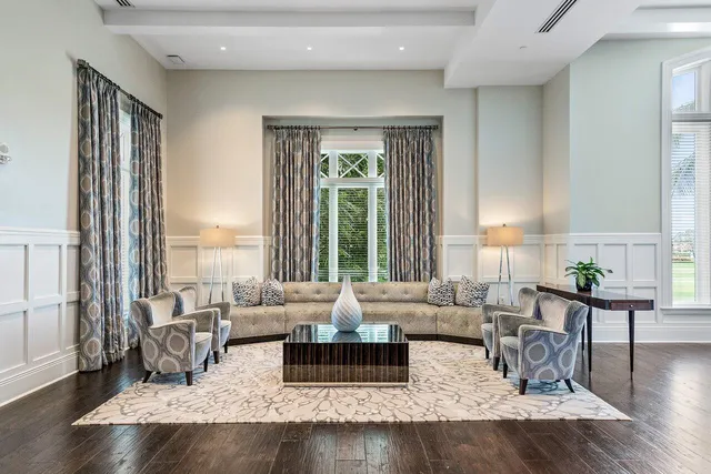 a living room with furniture large window and wooden floor