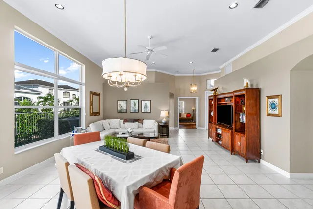 a view of a dining room and livingroom with furniture wooden floor a rug a flat screen tv a rug and a chandelier