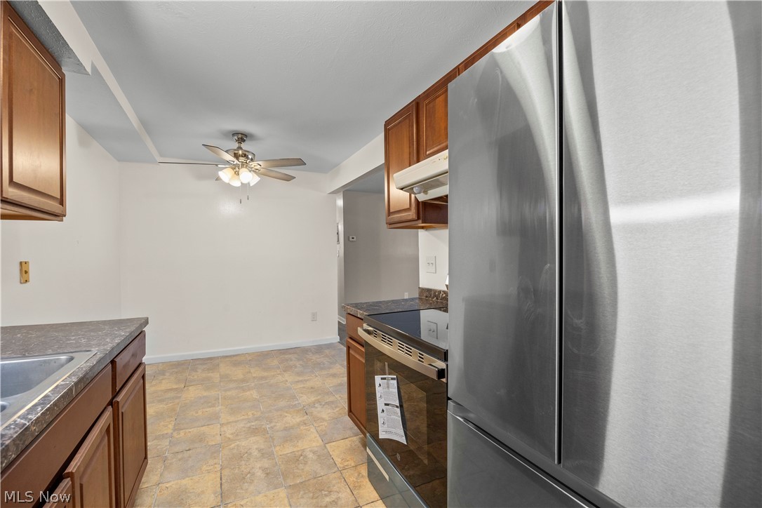 5382 Lee Road, Unit 102 Maple Heights, OH 44137 - Photo 15 of 25 Kitchen with stainless steel appliances, dark countertops, a ceiling fan, stone finish flooring, and wood finish cabinets