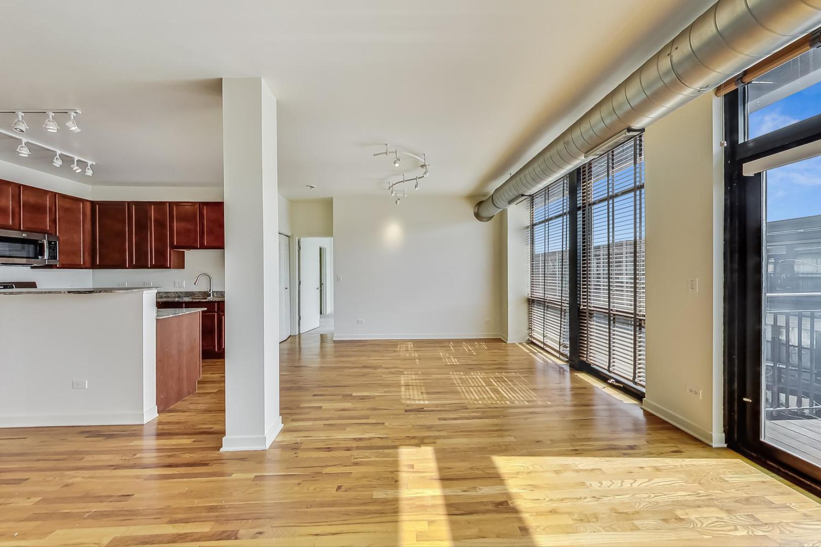 1151 West 14th Place, Unit 404 Chicago, IL 60608 - Photo 4 of 28 a view of a kitchen with kitchen island granite countertop wooden floor and a view of living room