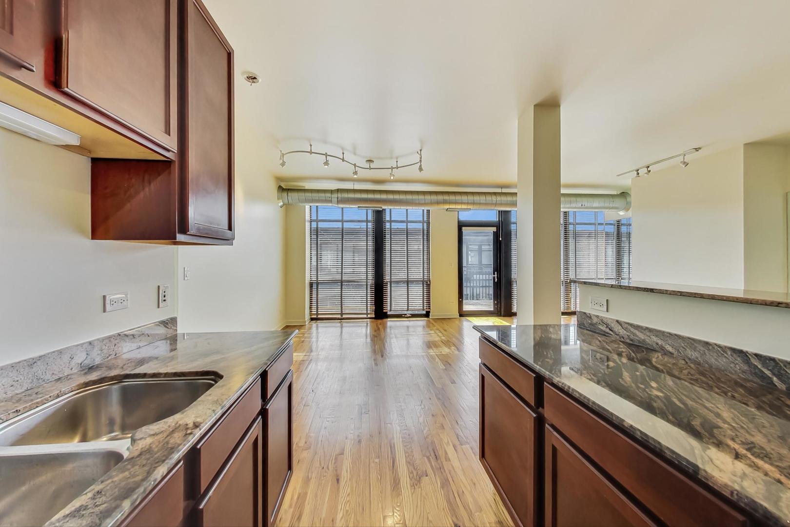 1151 West 14th Place, Unit 404 Chicago, IL 60608 - Photo 8 of 28 a kitchen with granite countertop a sink and a stove with wooden floor