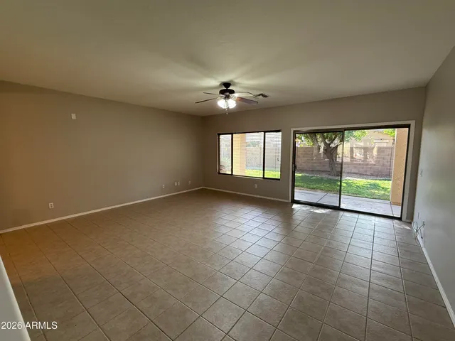 an empty room with windows and chandelier fan