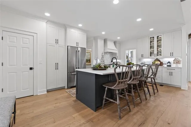 a dining hall with stainless steel appliances kitchen island granite countertop a table chairs and a refrigerator