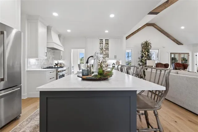 a kitchen with stainless steel appliances granite countertop a sink a stove a refrigerator and a dining table with wooden floor