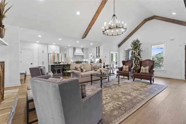 a living room with furniture a chandelier and kitchen view