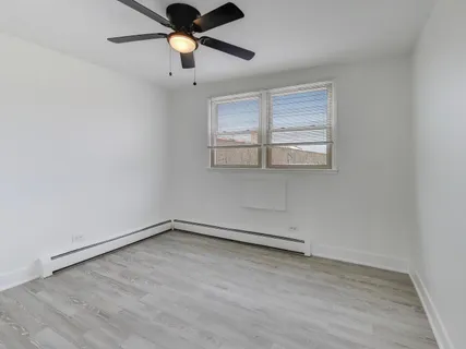 an empty room with ceiling fan and window