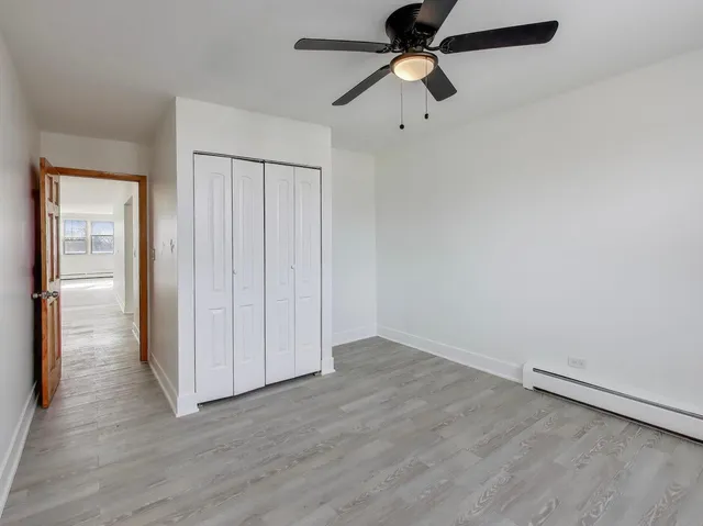 an empty room with wooden floor a ceiling fan & windows