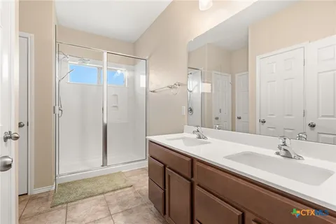 a bathroom with a double vanity sink mirror and shower