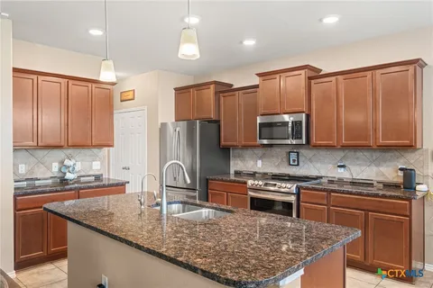 a kitchen with stainless steel appliances granite countertop a sink stove and refrigerator