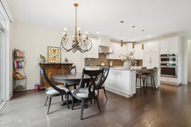 a view of a dining room and livingroom with furniture wooden floor a chandelier