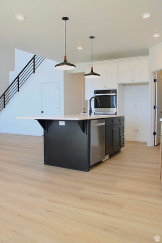 2613 Scarlet Road, Unit 258 Eagle Mountain, UT 84005 - Photo 10 of 32 Open-concept kitchen featuring a dark-toned island with light-colored countertop, stainless steel appliances, and two contemporary pendant lights