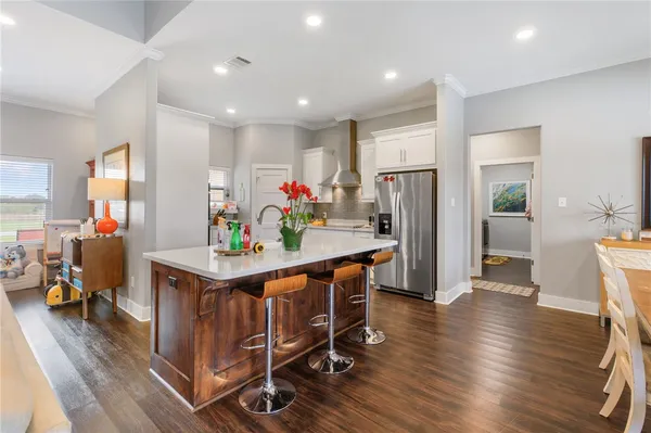 a view of kitchen with stainless steel appliances granite countertop a table chairs refrigerator and sink