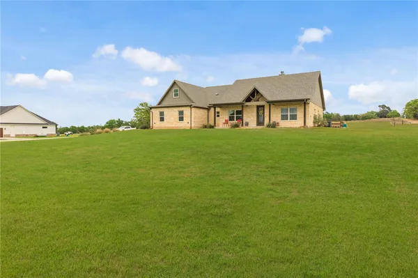 a view of a big house with a big yard and large trees