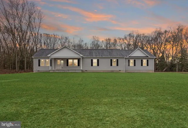 a front view of a house with a garden and trees