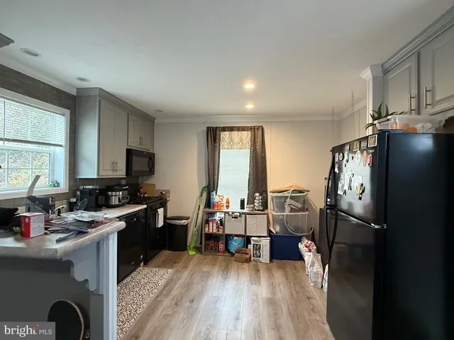 a kitchen with a refrigerator a stove and a dining table with wooden floor