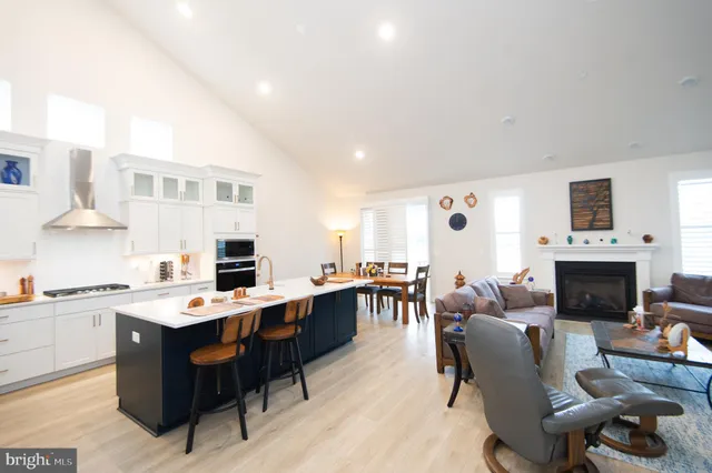 a living room with furniture a fireplace and a dining table with wooden floor
