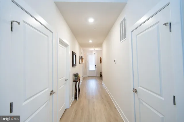 a view of a hallway with wooden floor and a bathroom