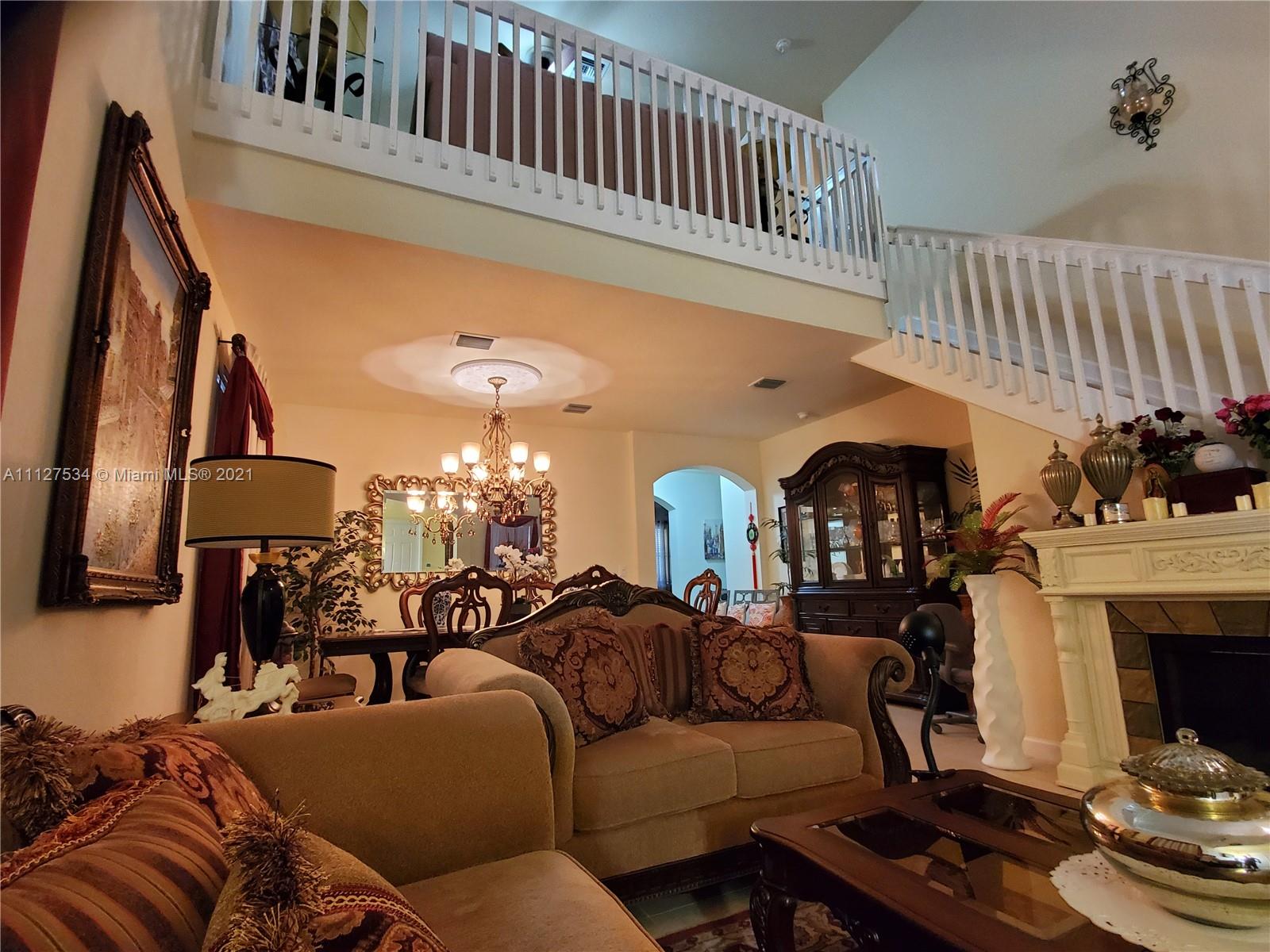 24075 Southwest 113 Passage Homestead, FL 33032 - Photo 16 of 35 a living room with furniture a fireplace and a chandelier