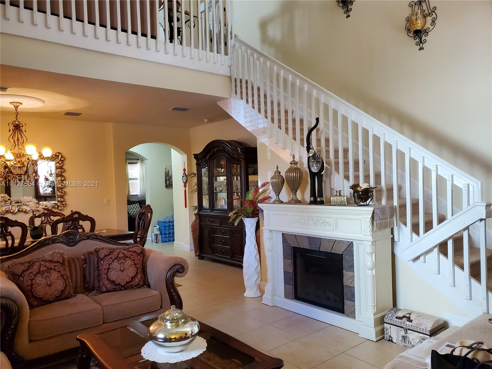 24075 Southwest 113 Passage Homestead, FL 33032 - Photo 17 of 35 a living room with furniture a fireplace and a chandelier