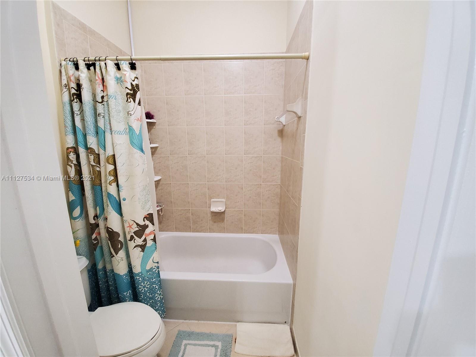 24075 Southwest 113 Passage Homestead, FL 33032 - Photo 32 of 35 a bathroom with a shower curtain and a toilet