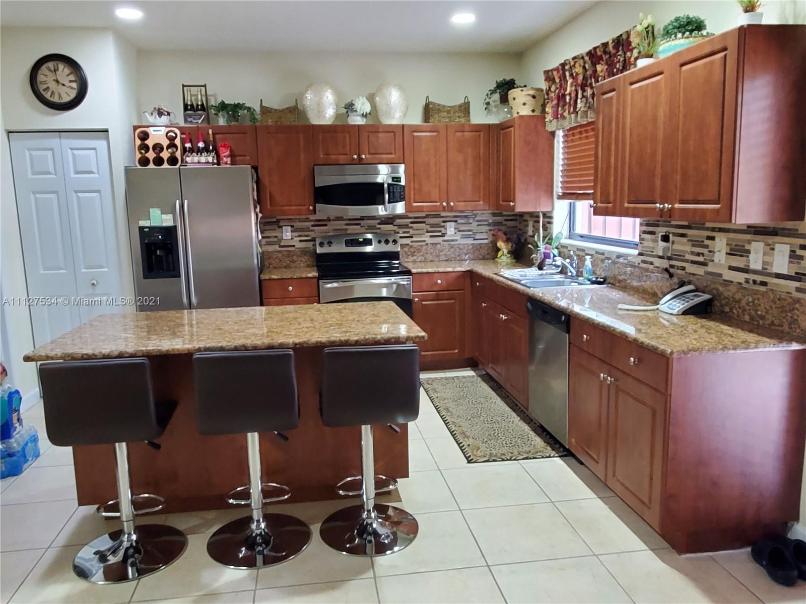24075 Southwest 113 Passage Homestead, FL 33032 - Photo 7 of 35 a kitchen with stainless steel appliances a sink dishwasher stove a refrigerator and a microwave with wooden cabinets
