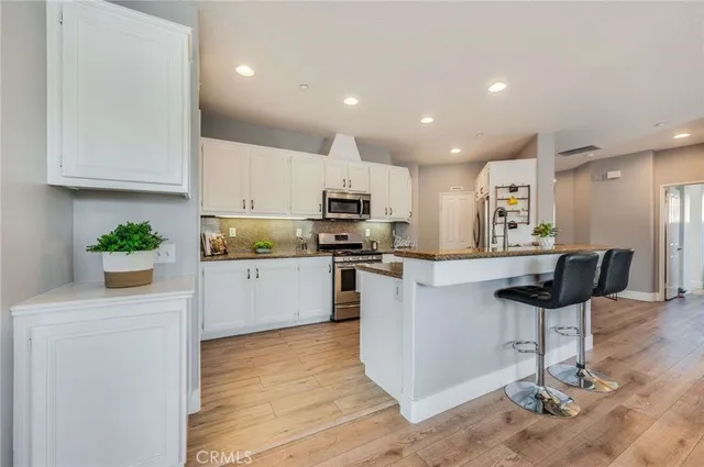 a kitchen with stainless steel appliances granite countertop a refrigerator a stove a sink and a microwave