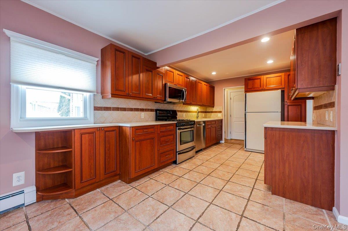 1674 Kroll Road East Meadow, NY 11554 - Photo 7 of 25 a kitchen with stainless steel appliances granite countertop wooden cabinets a stove top oven a sink and dishwasher