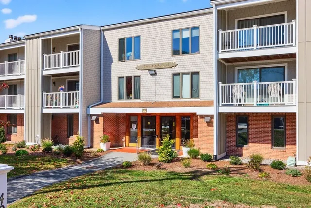 a front view of a building with a yard and fountain in front of it