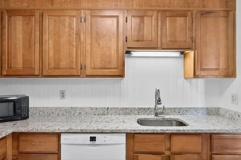 a kitchen with granite countertop a sink a stove and cabinets