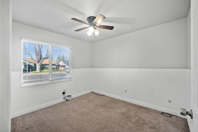 an empty room with a window and a fan