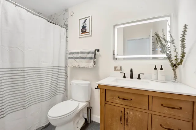 a bathroom with a granite countertop toilet sink and mirror