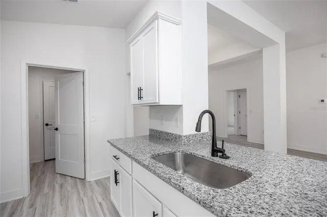 a kitchen with granite countertop a sink and a stove with wooden floors
