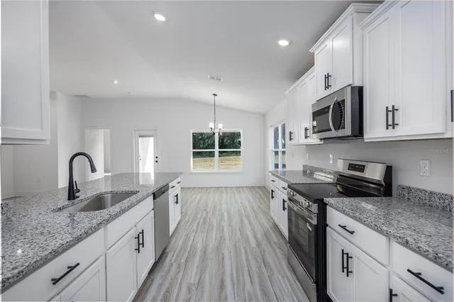 a kitchen with granite countertop a sink stove and cabinets