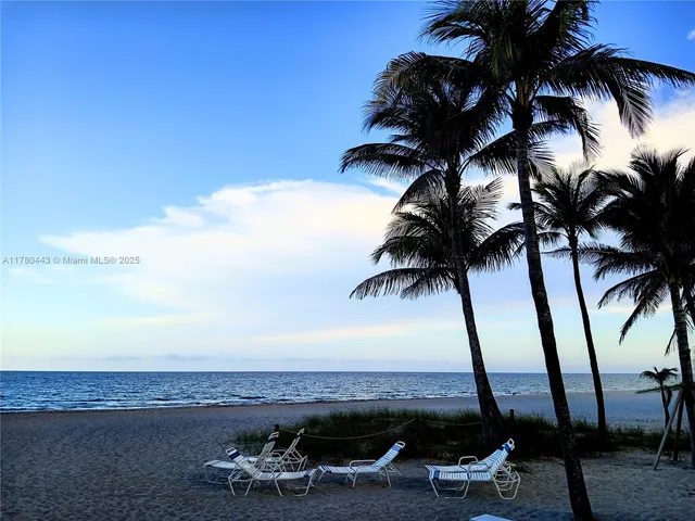 a view of ocean with boats and palm trees