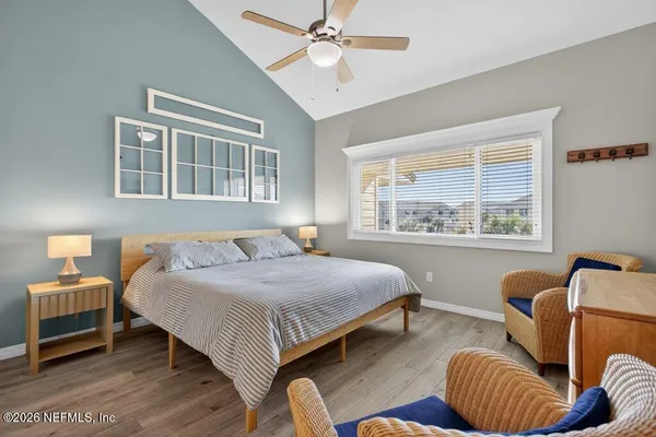 a bedroom with a bed couches chair and two windows