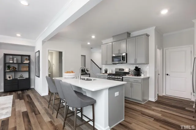 a kitchen with stainless steel appliances granite countertop a stove top oven a sink dishwasher and a refrigerator with wooden floor