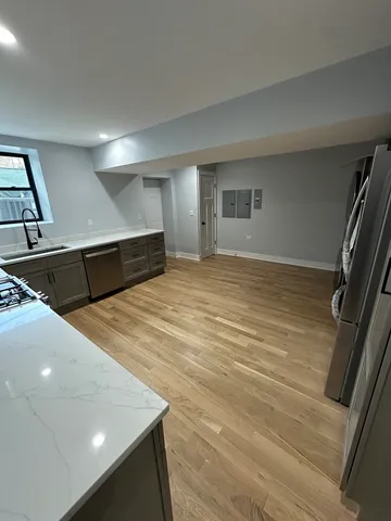 a view of kitchen and empty room with wooden floor