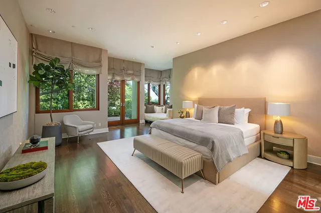 a spacious bedroom with a bed a table and large windows