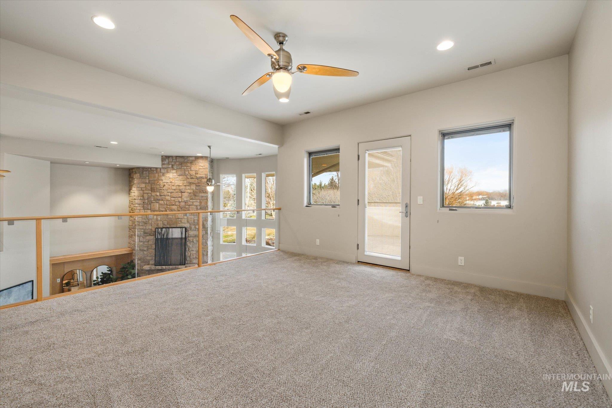 1400 North Razza Way Eagle, ID 83616 - Photo 25 of 50 Unfurnished living room featuring carpet floors, a ceiling fan, a large fireplace, and recessed lighting