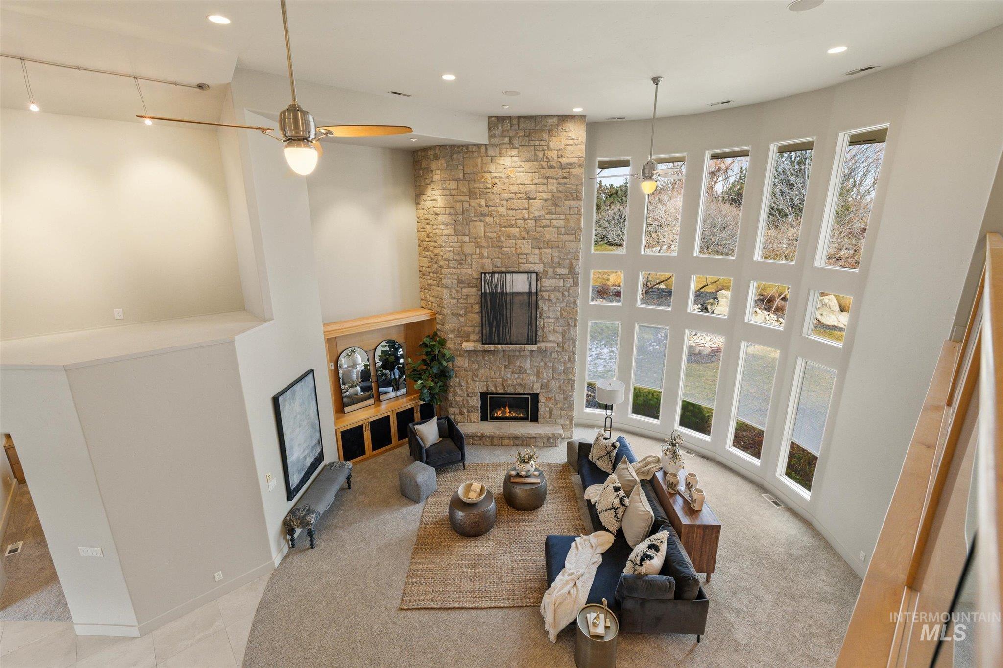 1400 North Razza Way Eagle, ID 83616 - Photo 26 of 50 Living area featuring carpet flooring, a stone fireplace, a ceiling fan, a high ceiling, and recessed lighting