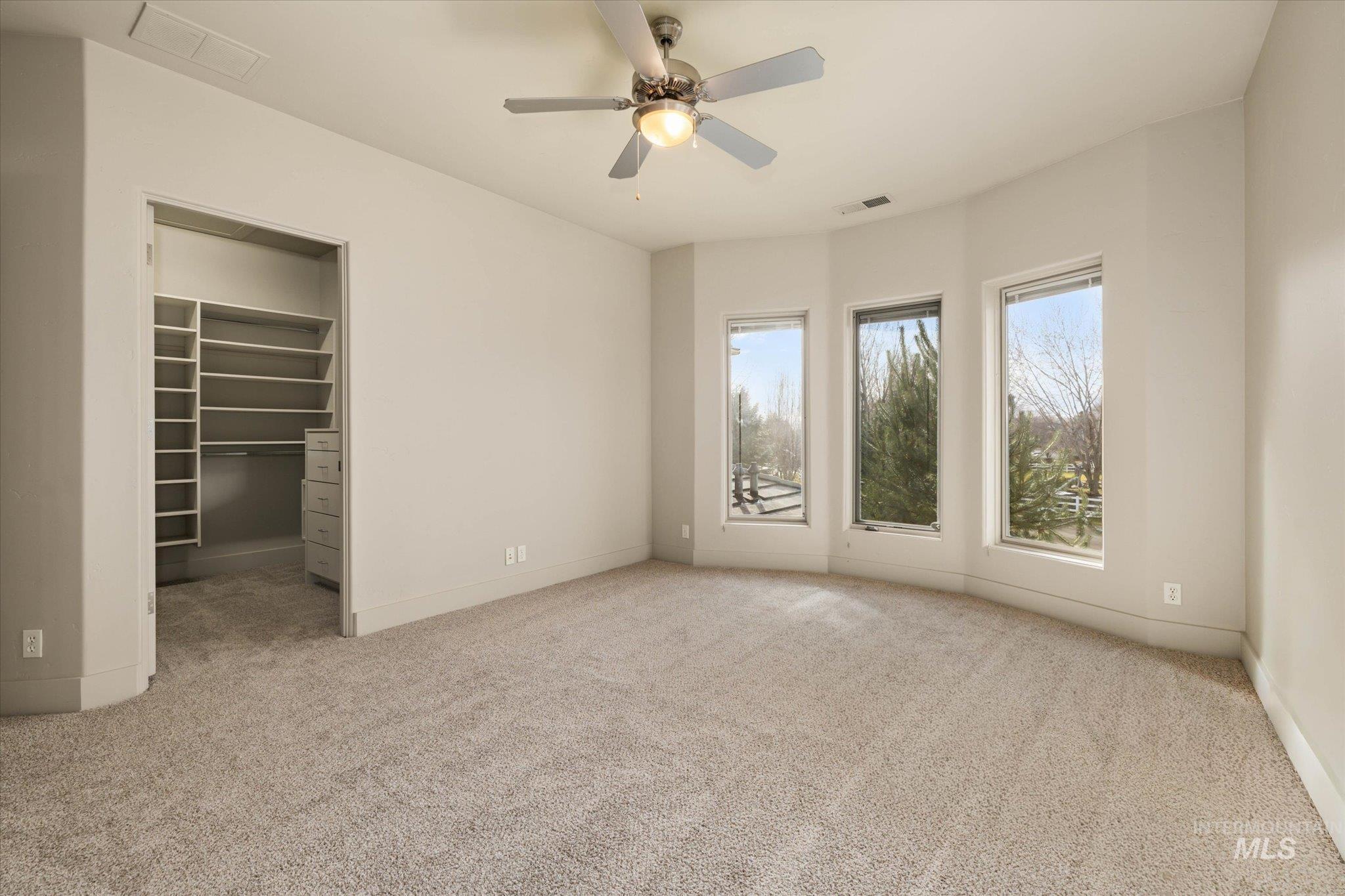 1400 North Razza Way Eagle, ID 83616 - Photo 29 of 50 Unfurnished bedroom with a spacious closet, light colored carpet, and a ceiling fan