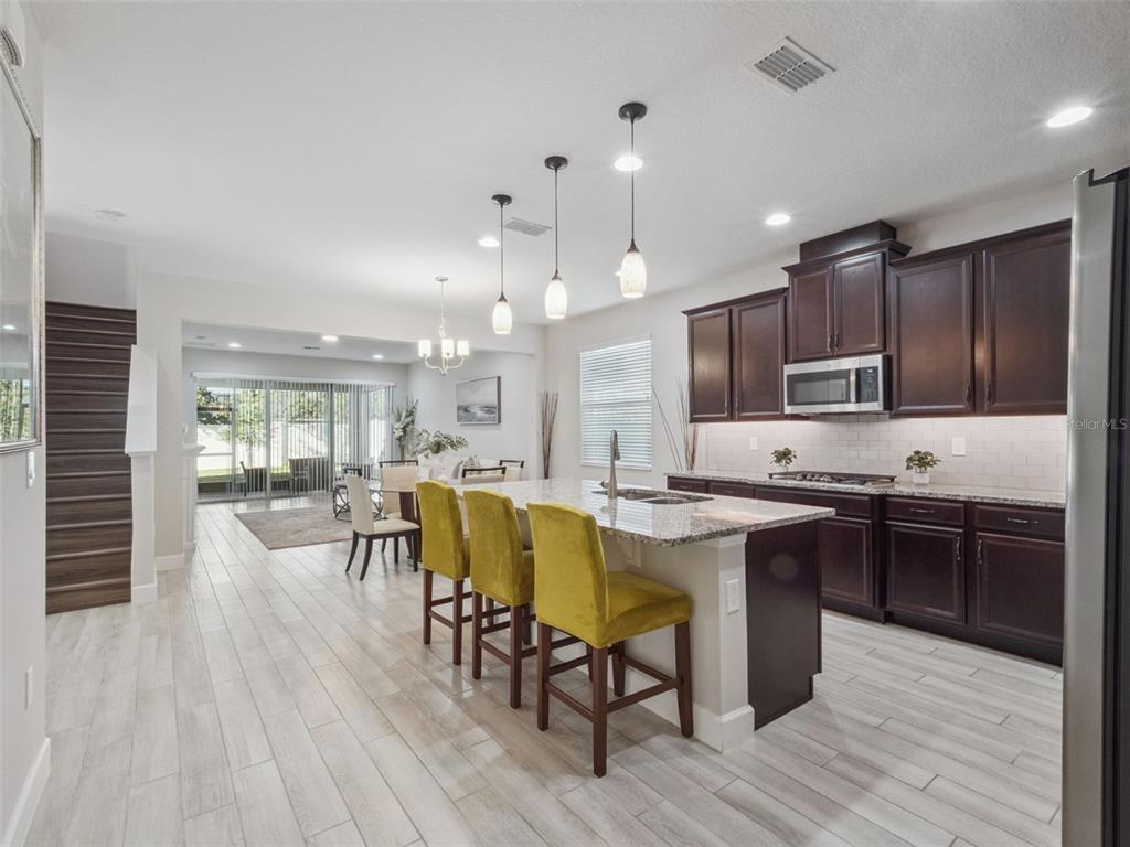 14345 Wabasso Loop Winter Garden, FL 34787 - Photo 4 of 31 a kitchen with stainless steel appliances granite countertop wooden floors stove top oven with cabinets and wooden floor