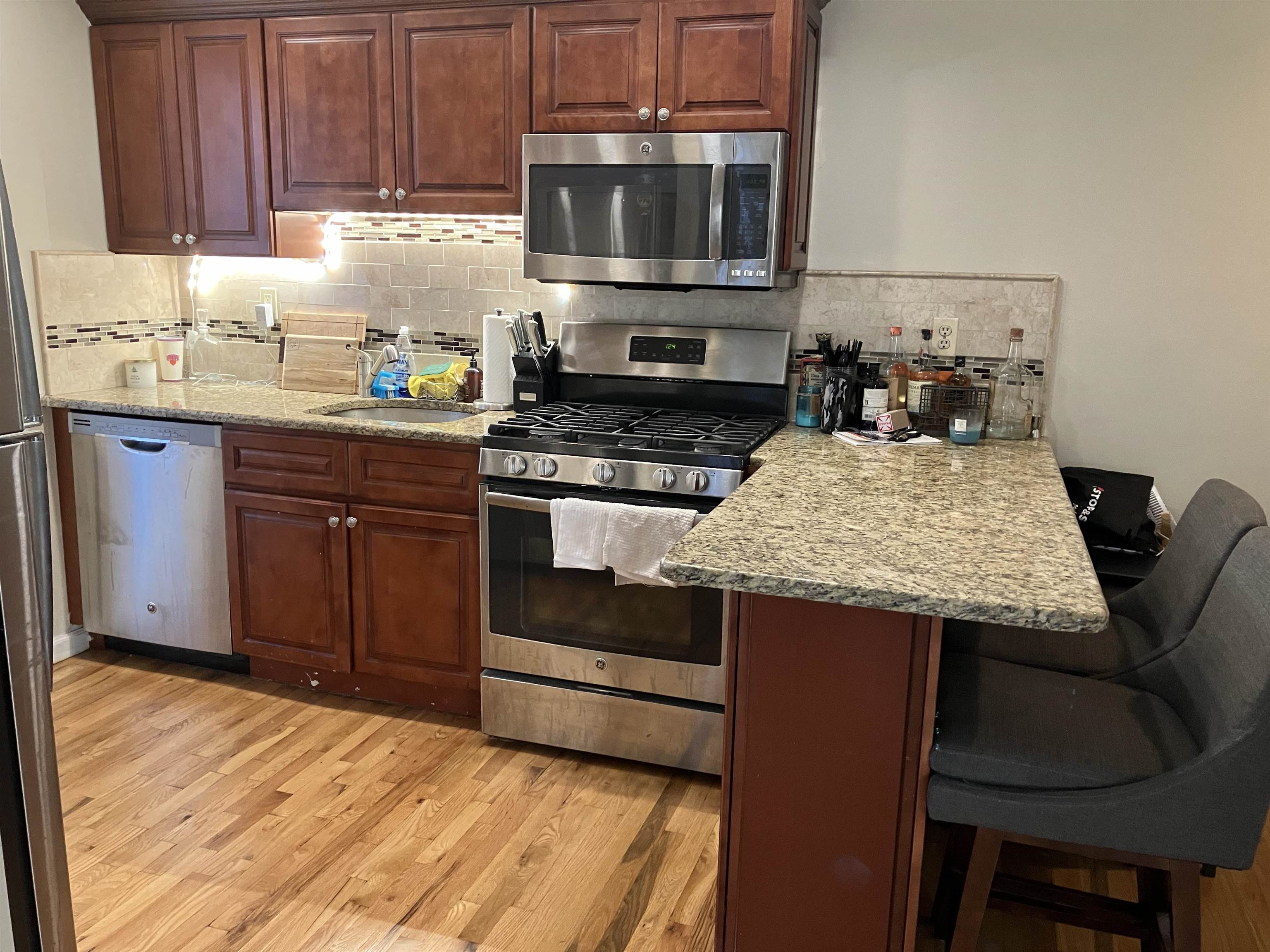409 Adams Street, Unit 8 Hoboken, NJ 07030 - Photo 6 of 17 a kitchen with granite countertop wooden cabinets and stainless steel appliances