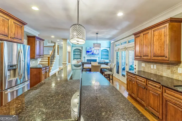 a view of a kitchen with kitchen island granite countertop a large window cabinets a sink and stainless steel appliances