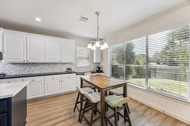 a kitchen with a table chairs and white cabinets