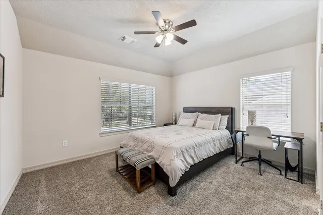 a spacious bedroom with a bed a chandelier and a window